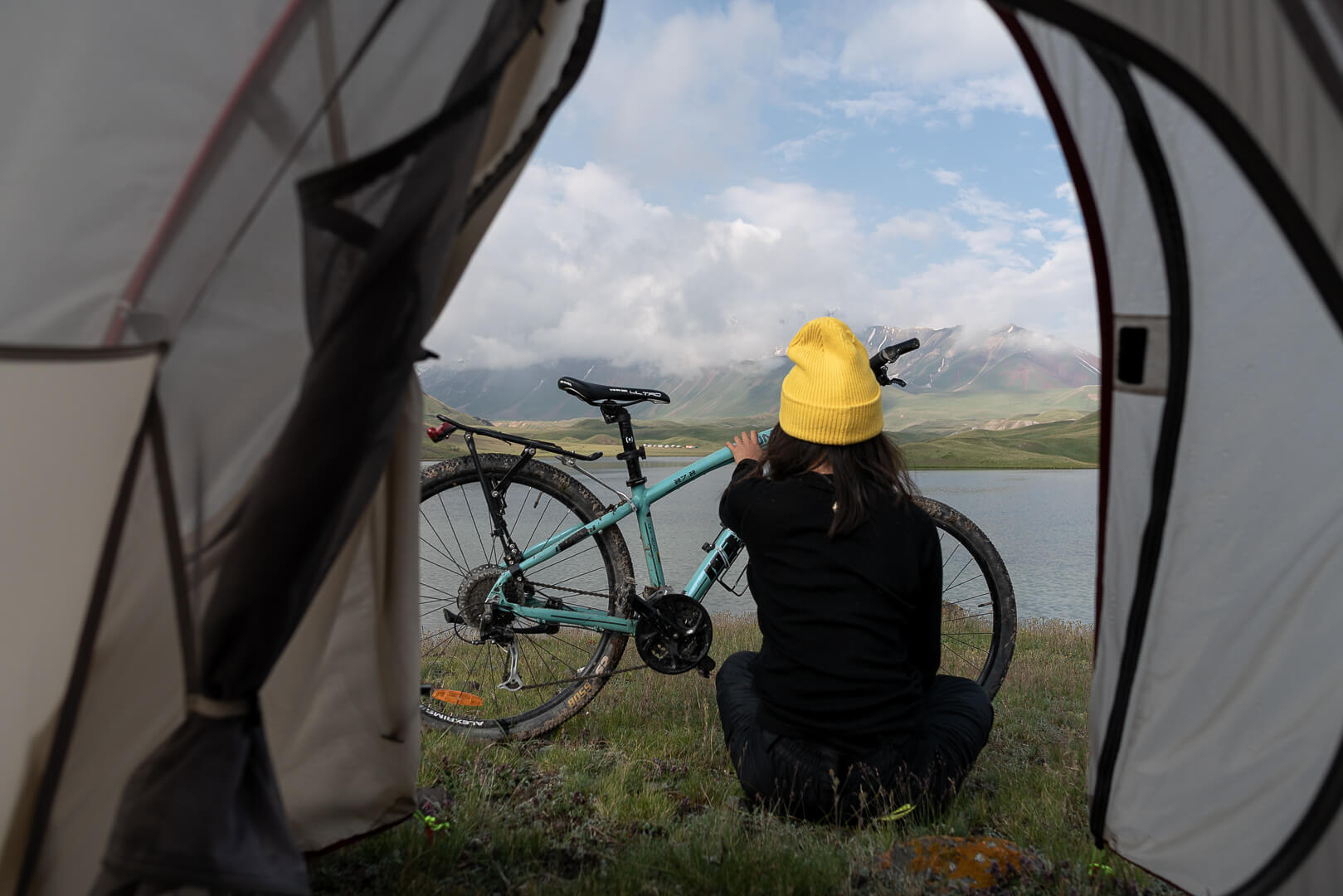 Marsha Jean and her bike in front of a beautiful lake in Central Asia.