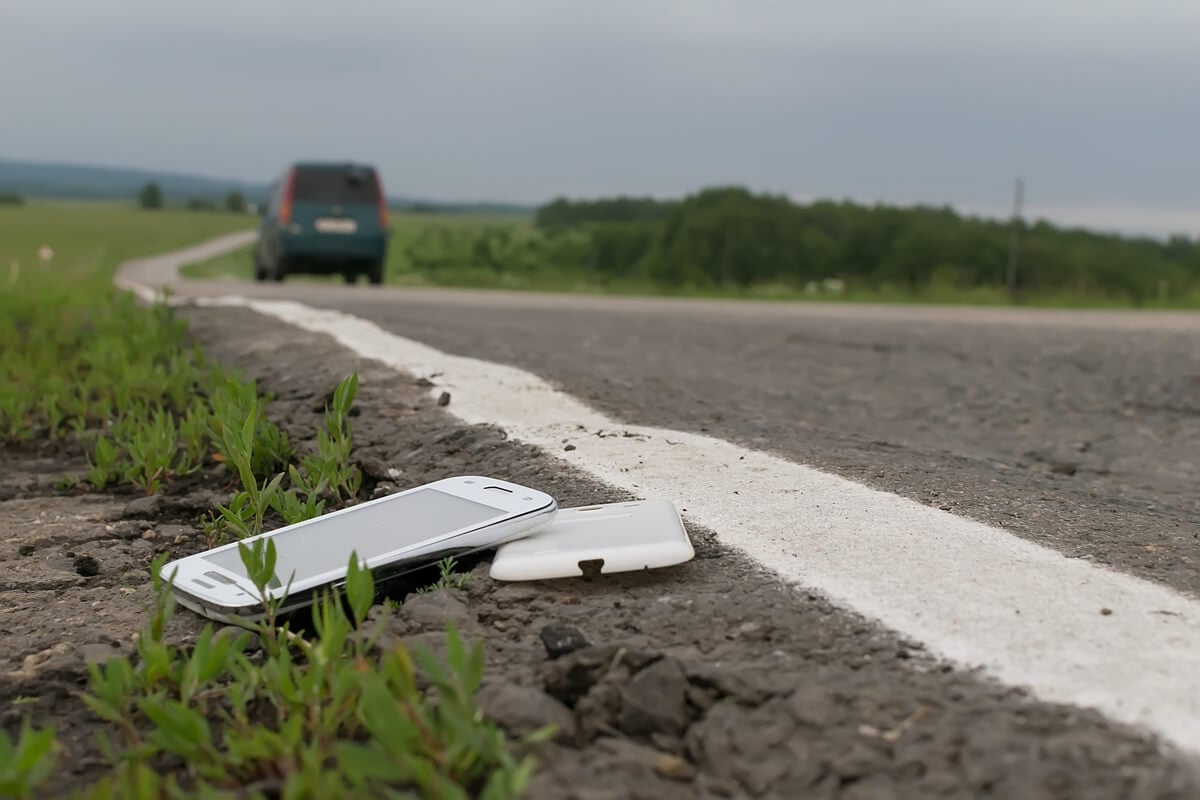 A van driving off with a broken phone on the side of the road
