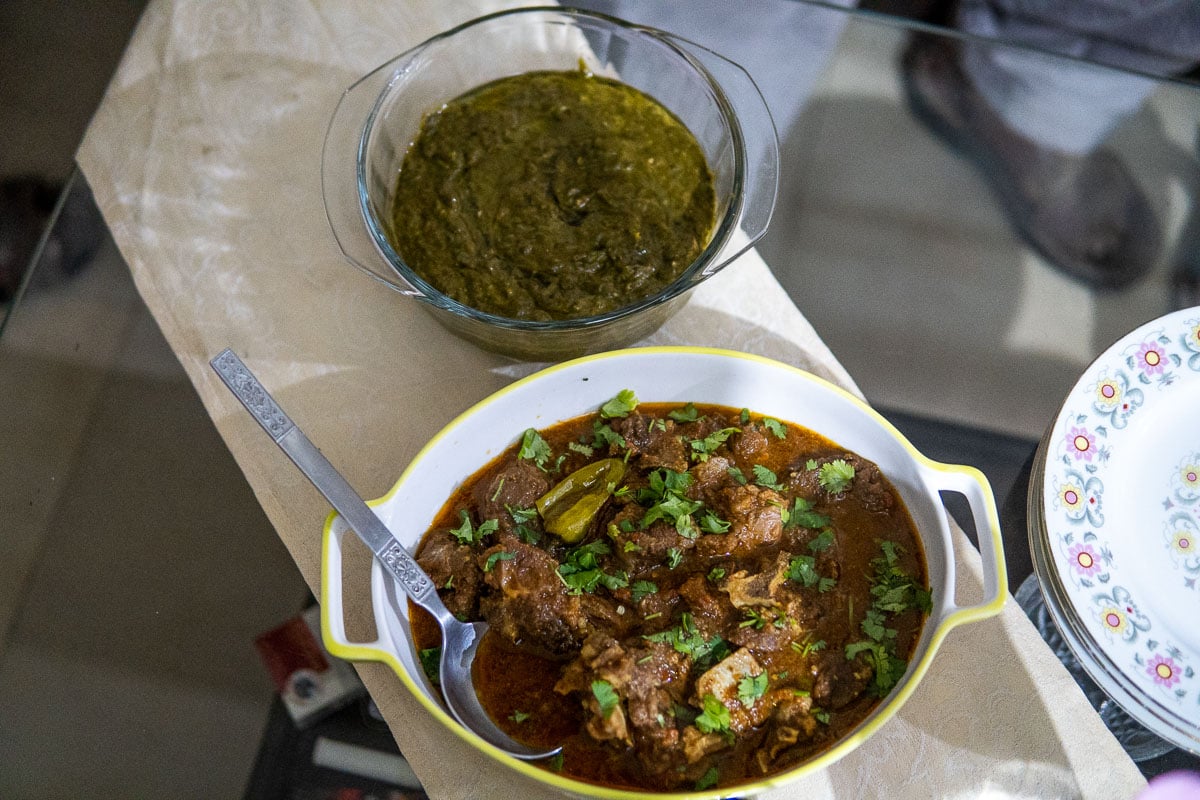 bowl of pakistani karahi and green saag paneer on a glass table