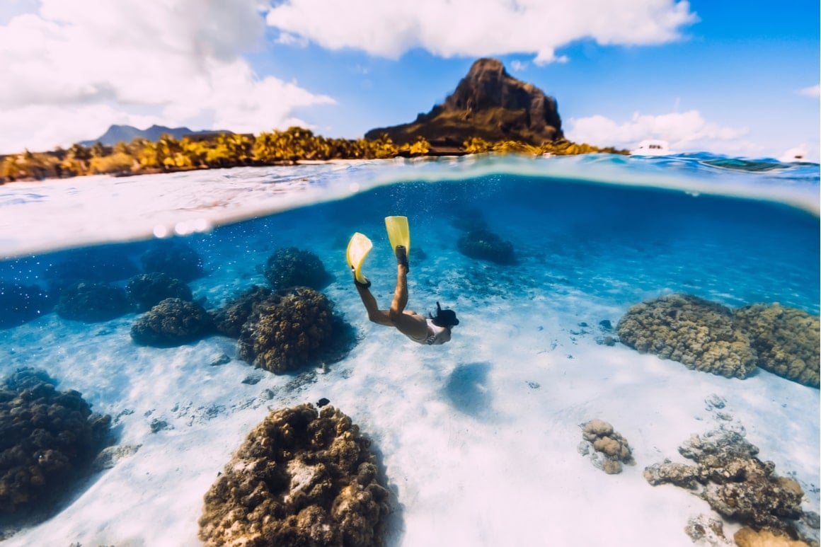girl freediving underwater in the tropics with yellow flippers on