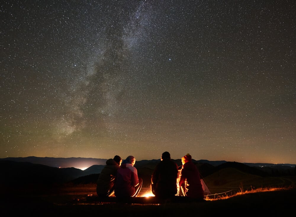 Four friends sit around a campfire after a day of spearfishing.