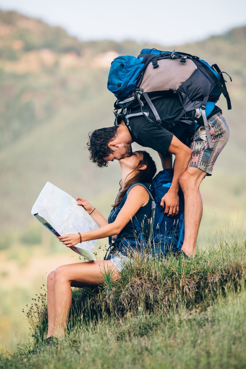 backpacking couple kissing as girl holds a map while traveling