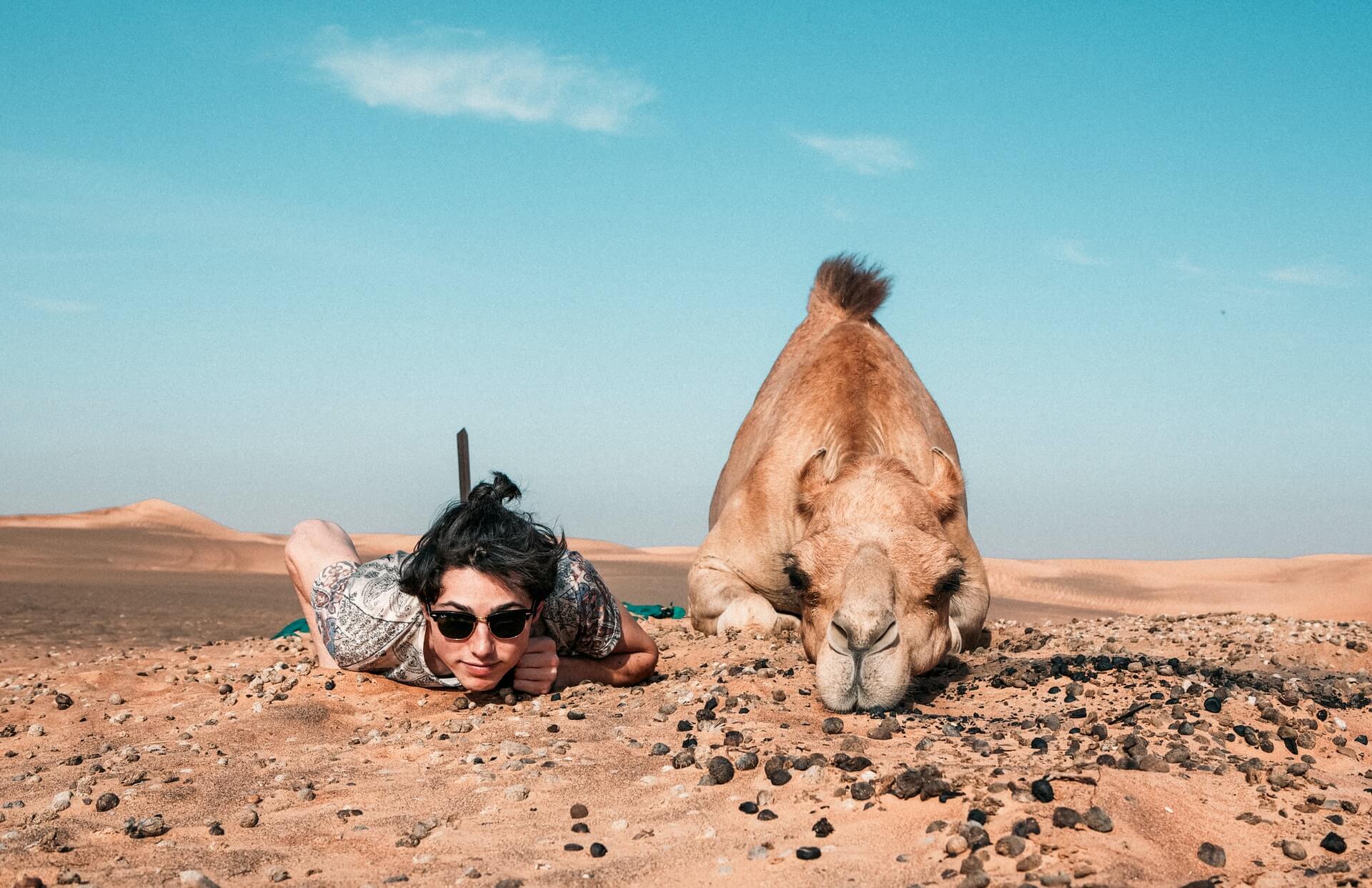 A solo traveller backpacking the Middle East posing with a camel.