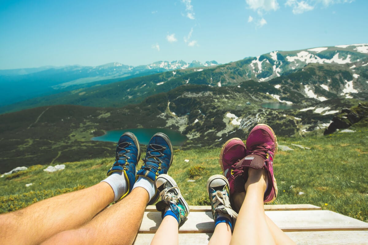 three pairs of feet family traveling overlooking green mountains and a lake