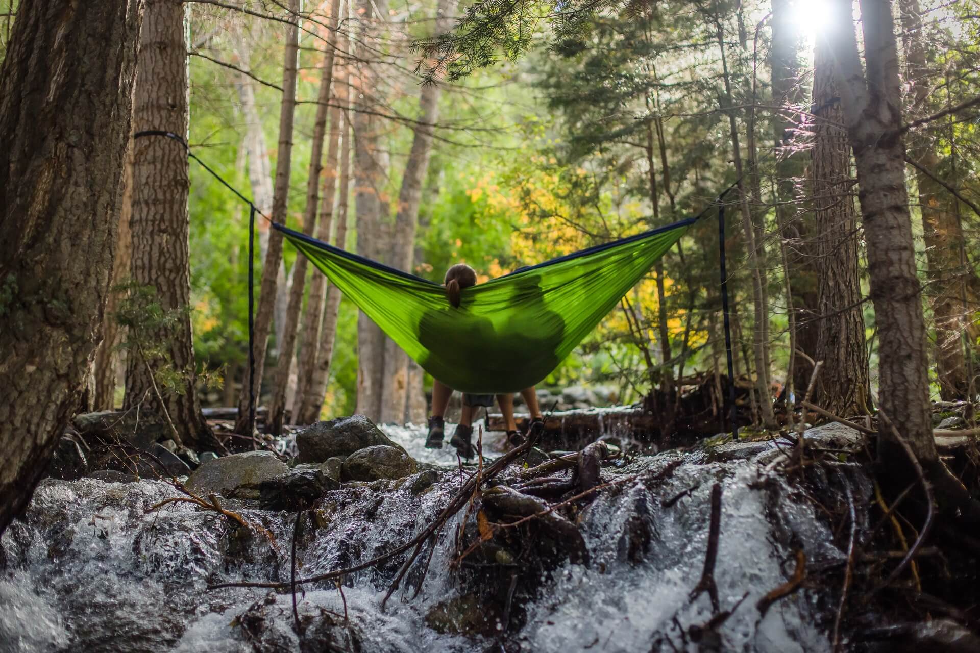 two people sitting in a green hammock while camping as a couple 