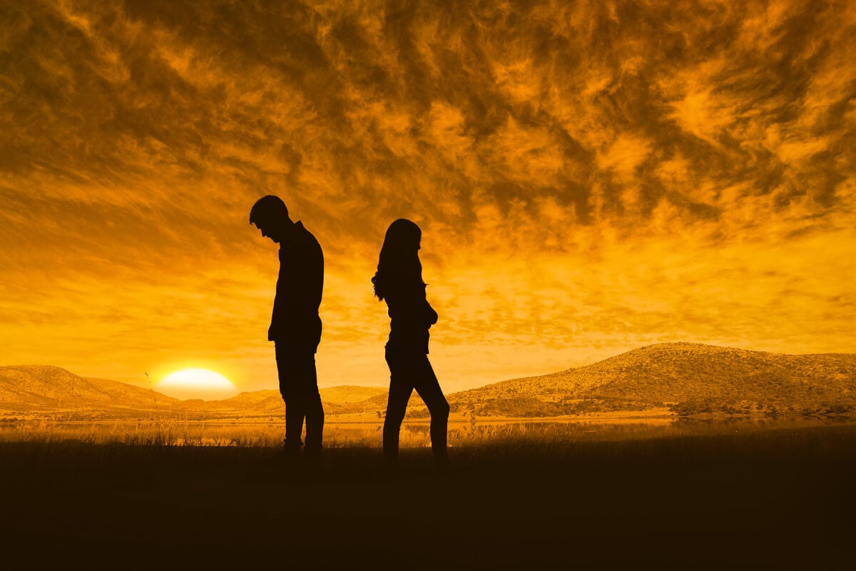 couple standing apart under orange sunset