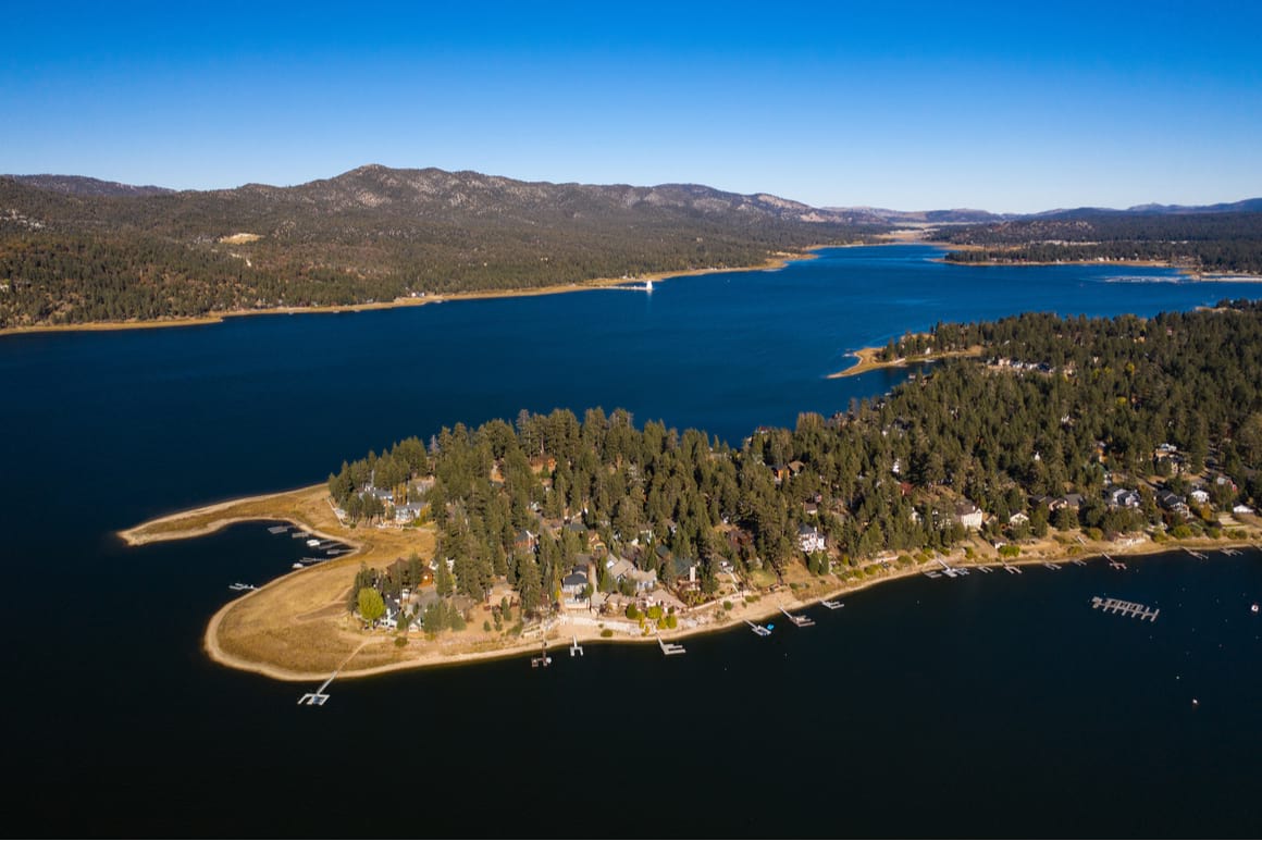 aerial view of Big Bear Lake Central with blue sky and calm waters, showing a peninsular of Big Bear Village