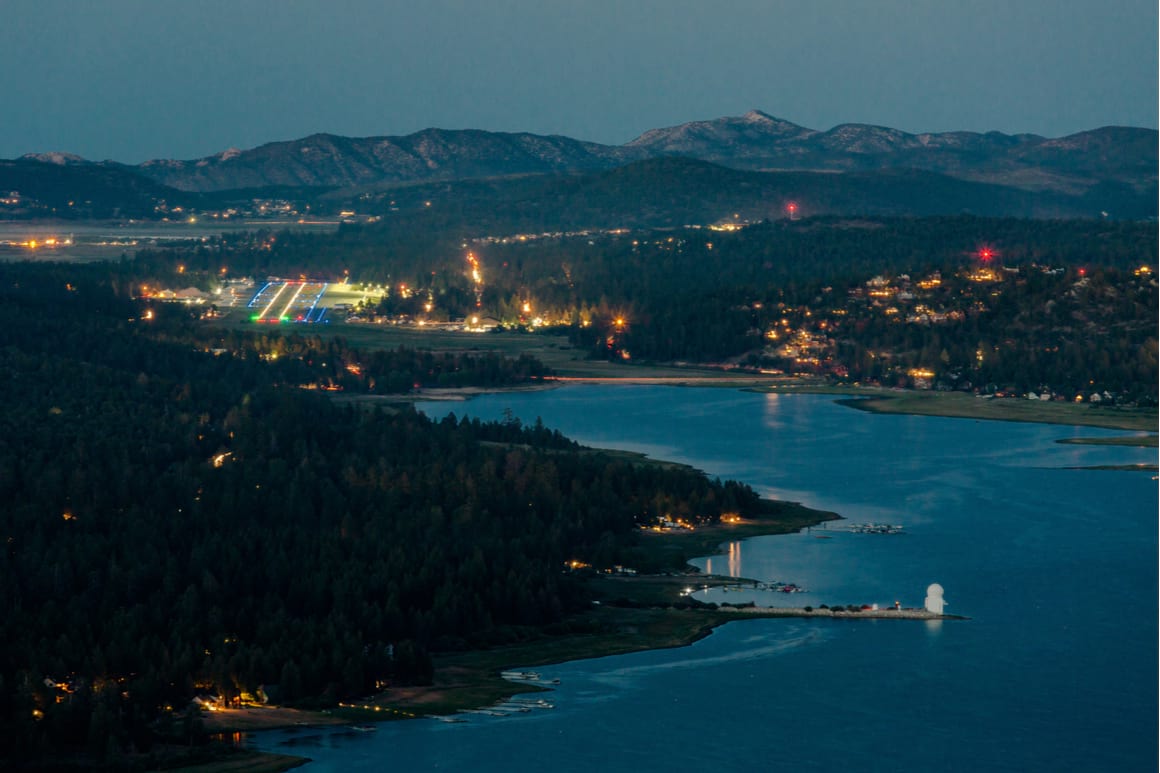 Fawnskin village on big bear lake lit up at night showing mountains, forest and lake 