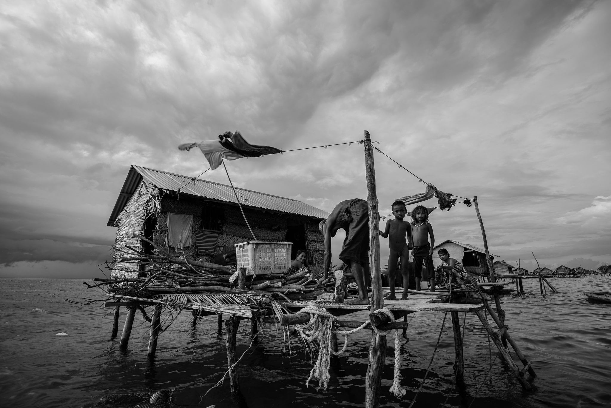 three Bajua sea nomads stand on their floating home 