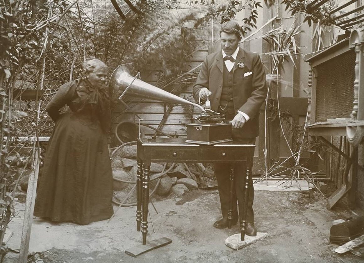 A historical photo of an indigenous Aboriginal woman having her speech and language recorded