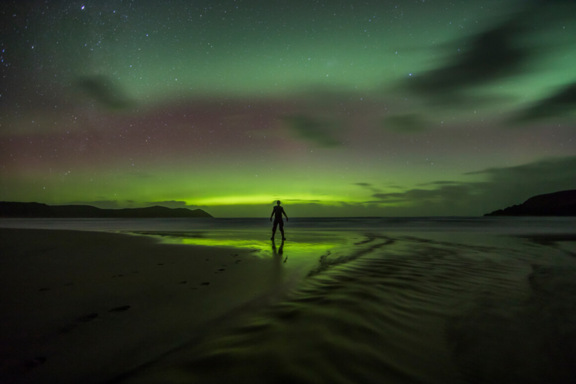 A photo of a backpacker in Tasmania celebrating seeing the Southern Lights on a beach