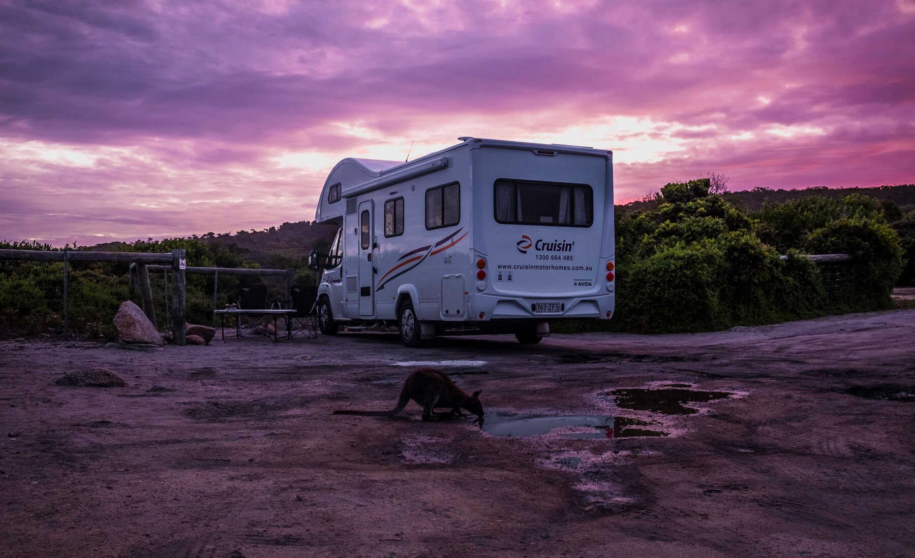 A vibrant sunset over an RV motorhome parked by a popular beach in Tasmania