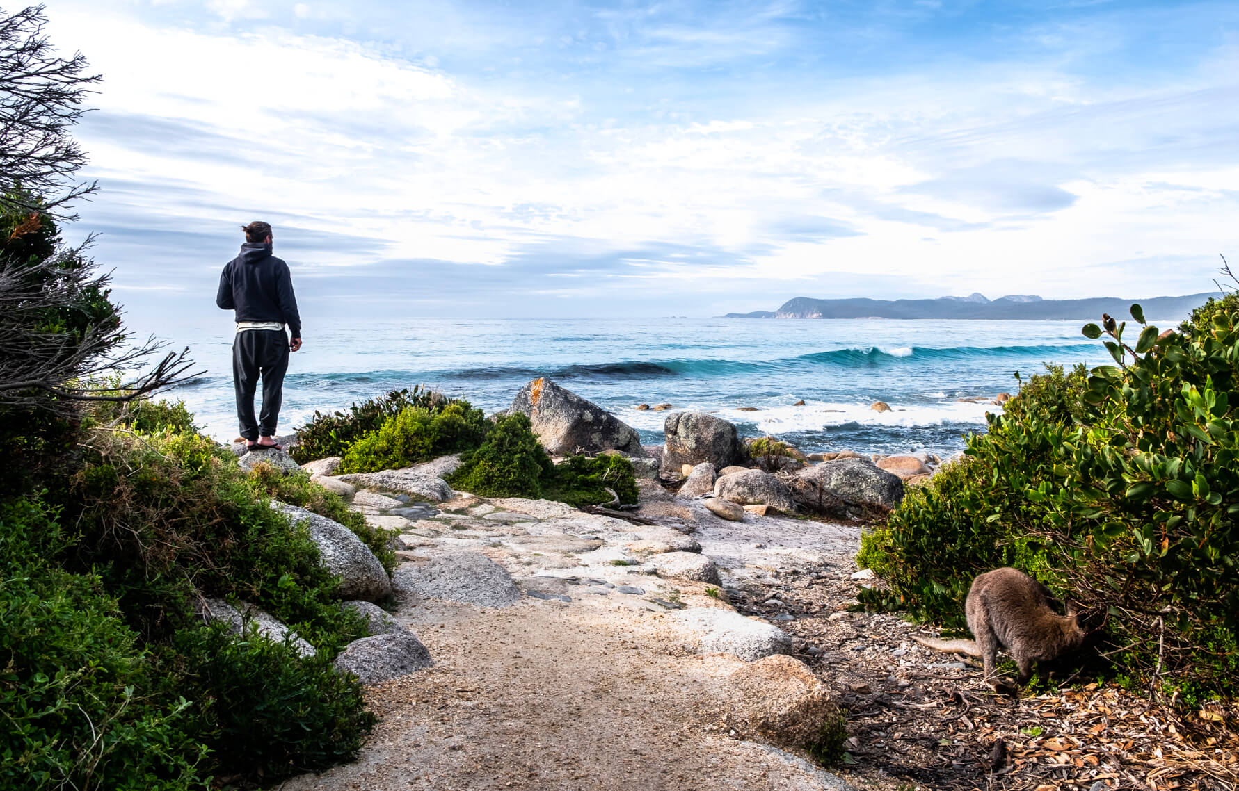 A backpacking vanlifer looks out at Friendlies Beach on the Freycinet Peninsula