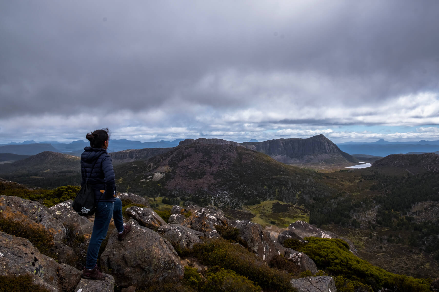 A backpacker hiking in Tasmania looks out at the Central Plateau Conservation Area