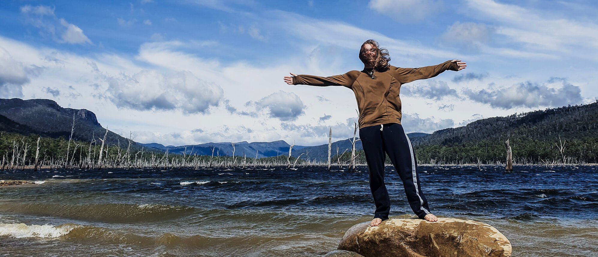 A man backpacking Tasmania poses in front of a lake near The Walls of Jerusalem