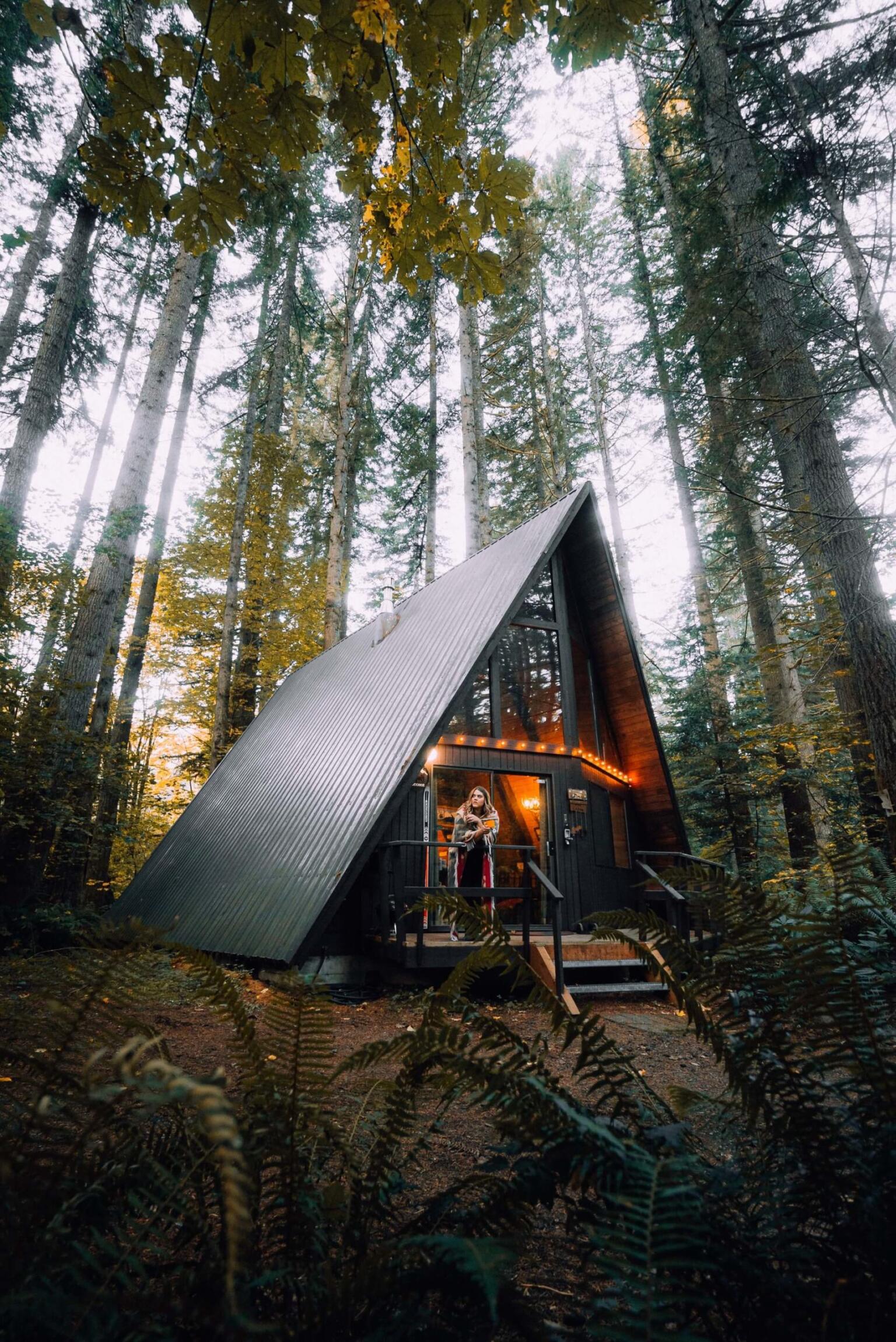 girl standing on deck of forest cabin what is airbnb