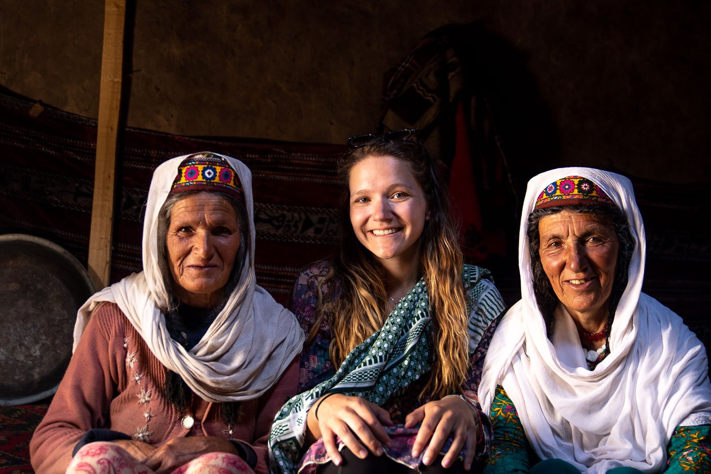 gitl sitting with two elders in their home in a remote region in pakistan homestaying