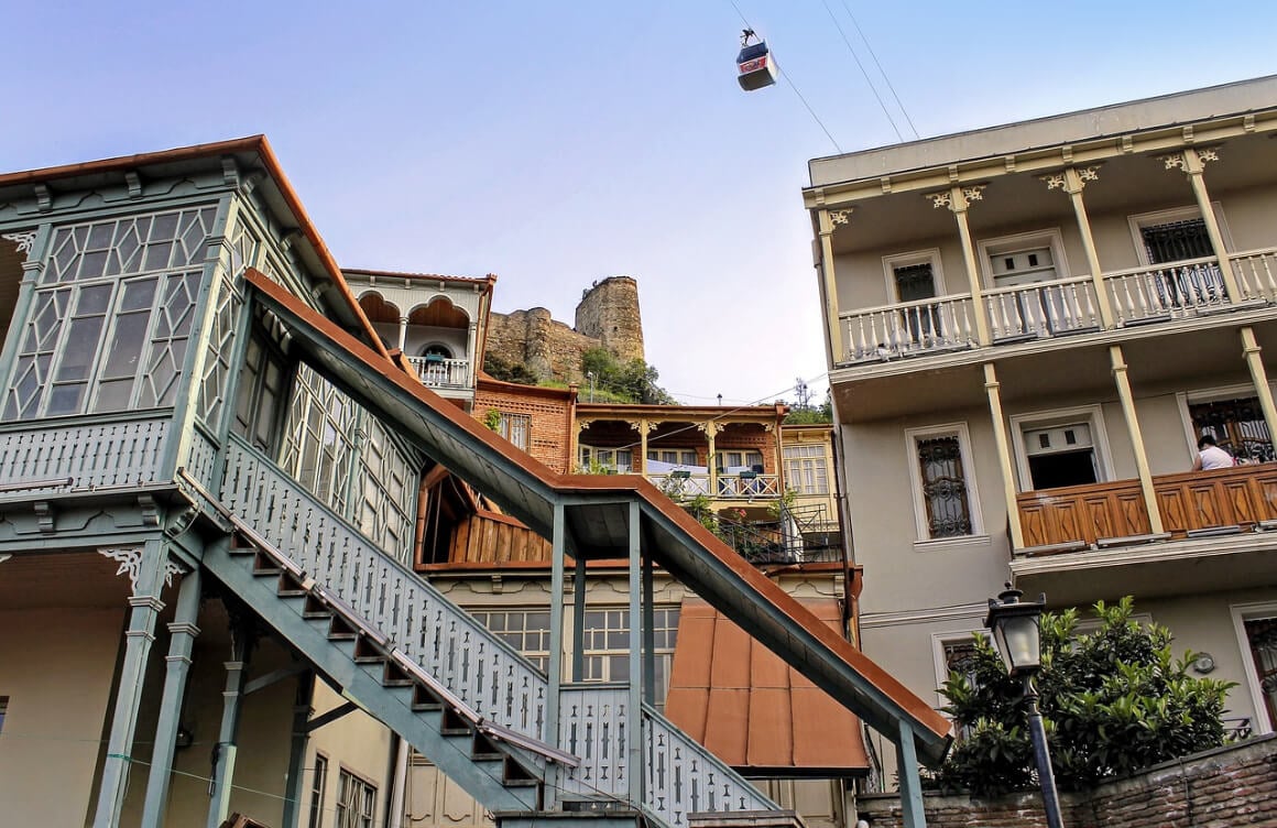 view of terraces in Tbilisi old town with a cable car passing overhead