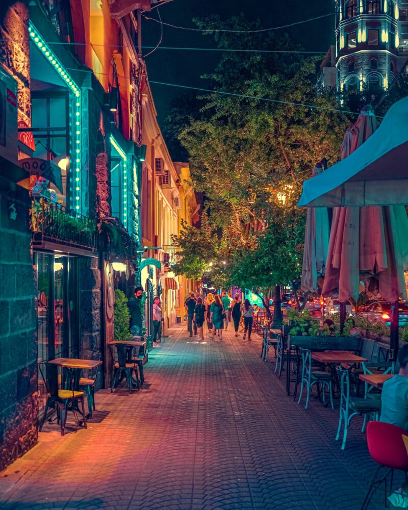 a night time street view of a cafe with people walking in the distance.