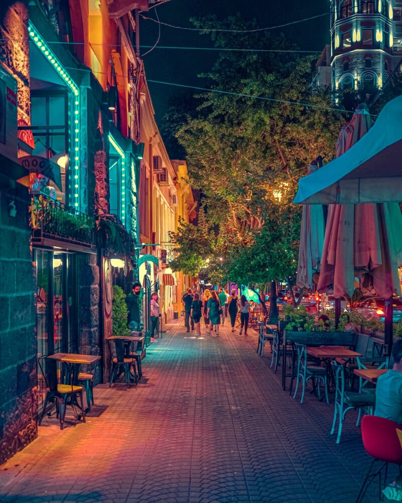 a night time street view of a cafe with people walking in the distance.