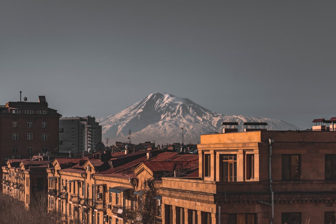 tops of buildings with snow-covered mountain on the background