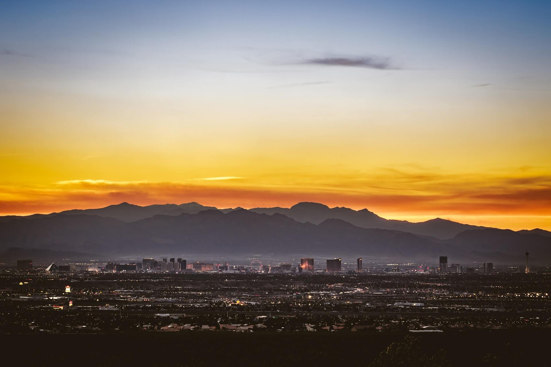 orange and yellow sunset and blue mountain shadows towering over las vegas 