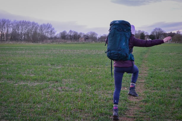 Woman jumping wearing the Gregory Deva 60 backpack. 