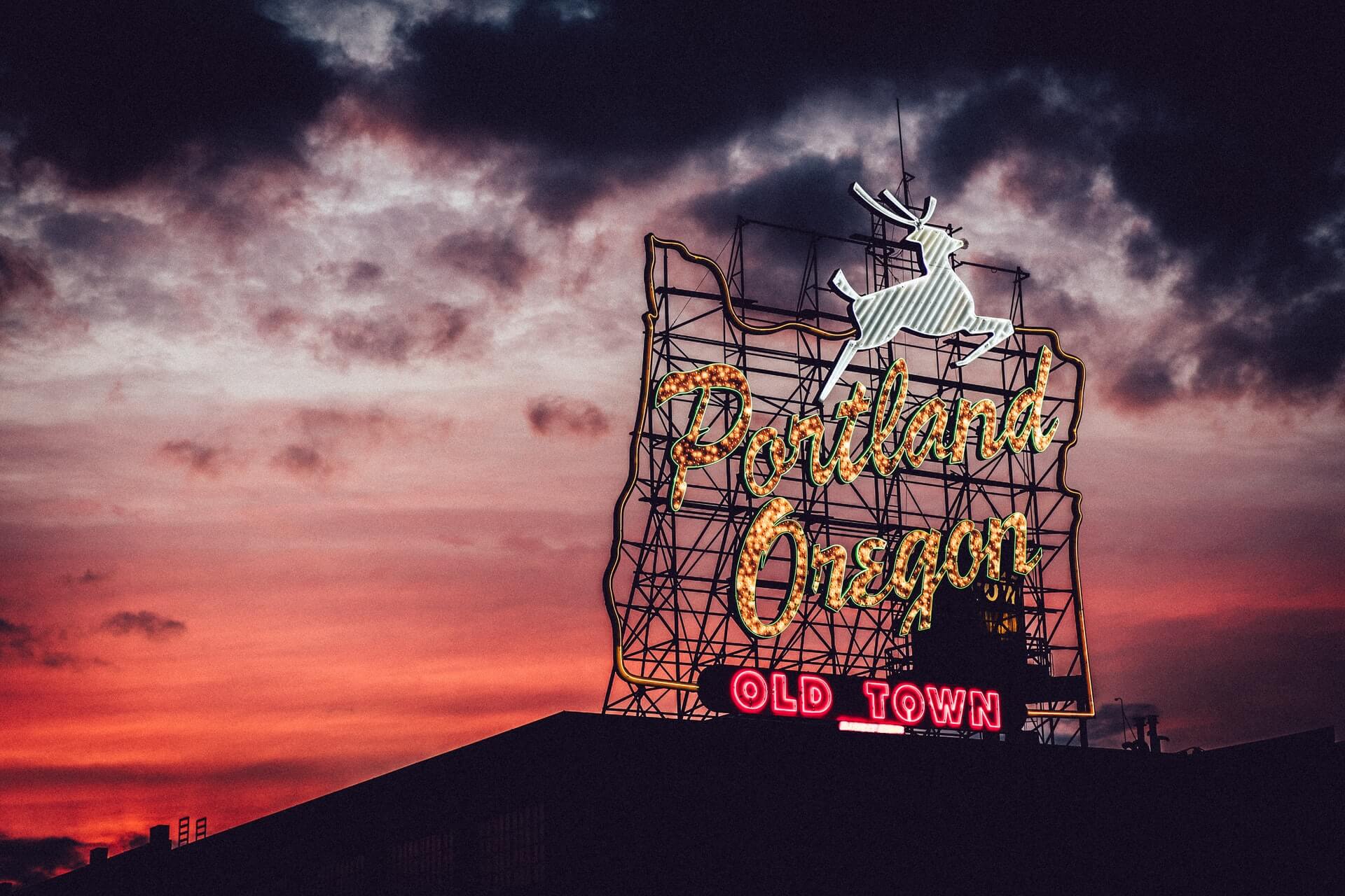 gold portland oregon sign with a red-pink sunset in the background