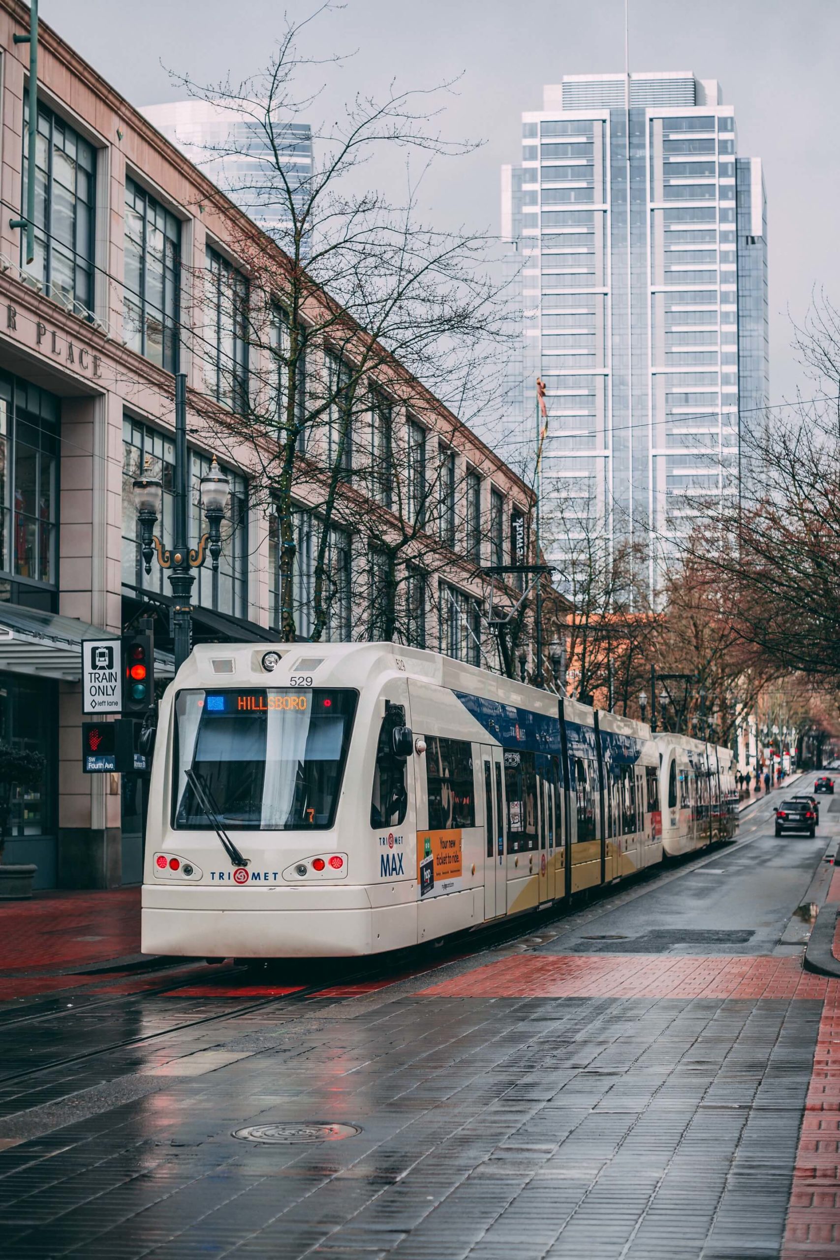 tram pulling up to rainy stop on a cobblestone street in portland