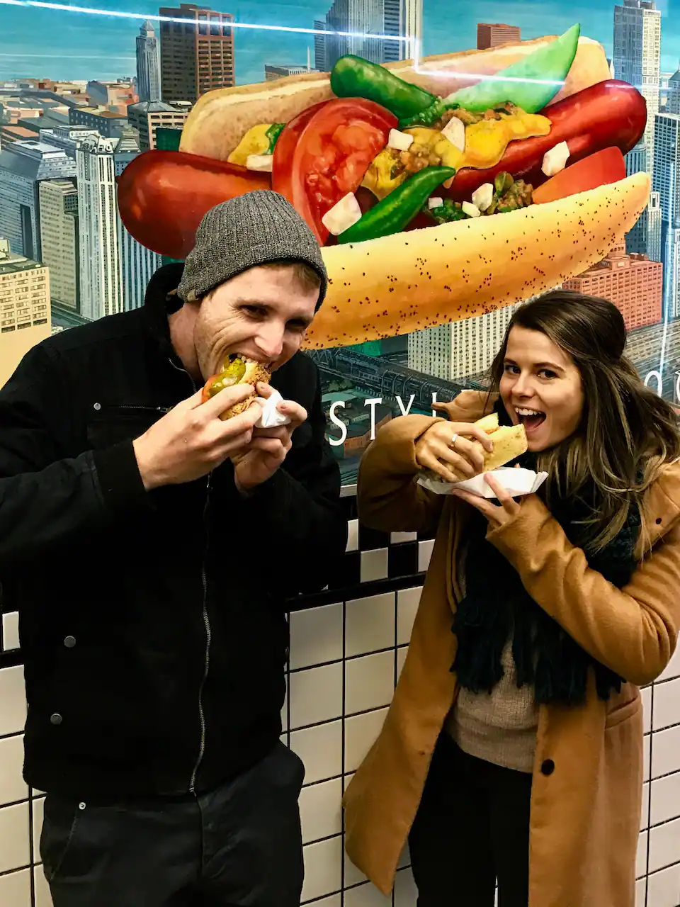 two people eating chicago style hot dogs on a trip to chicago