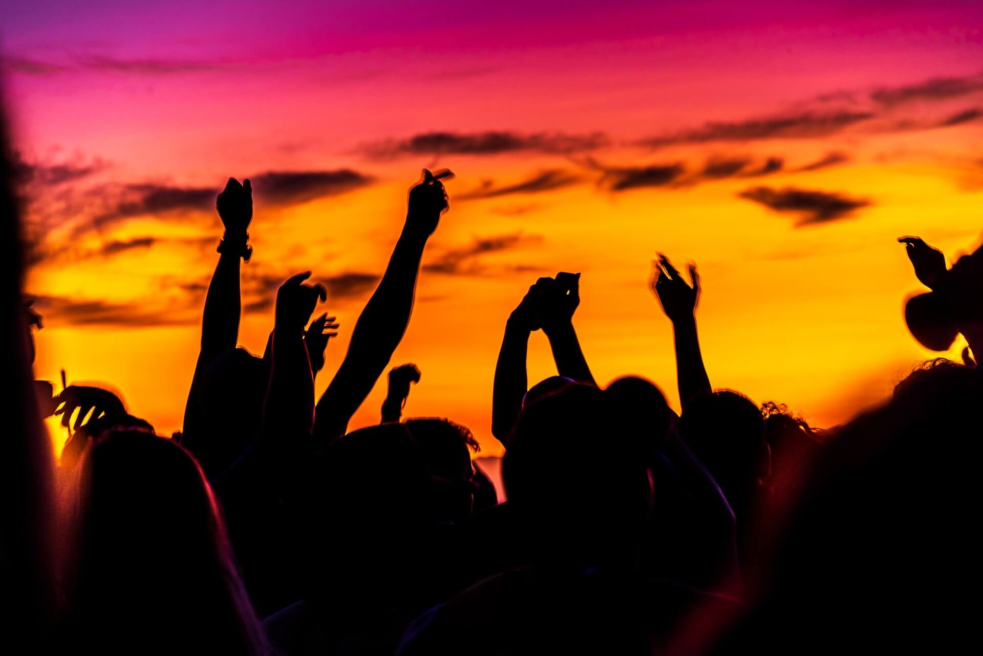 people dancing under a yellow orange and pink sky