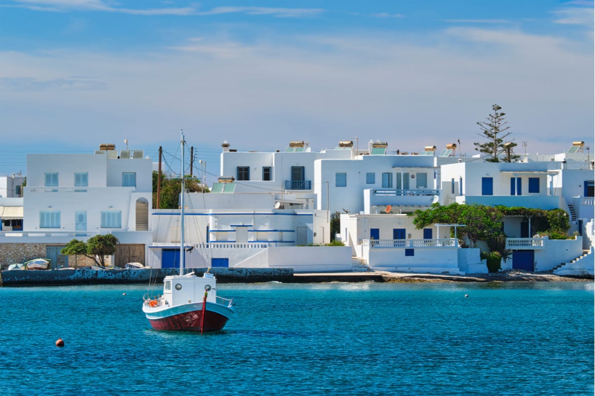 Blue ocean and sail boat with greek, blue and white houses behind