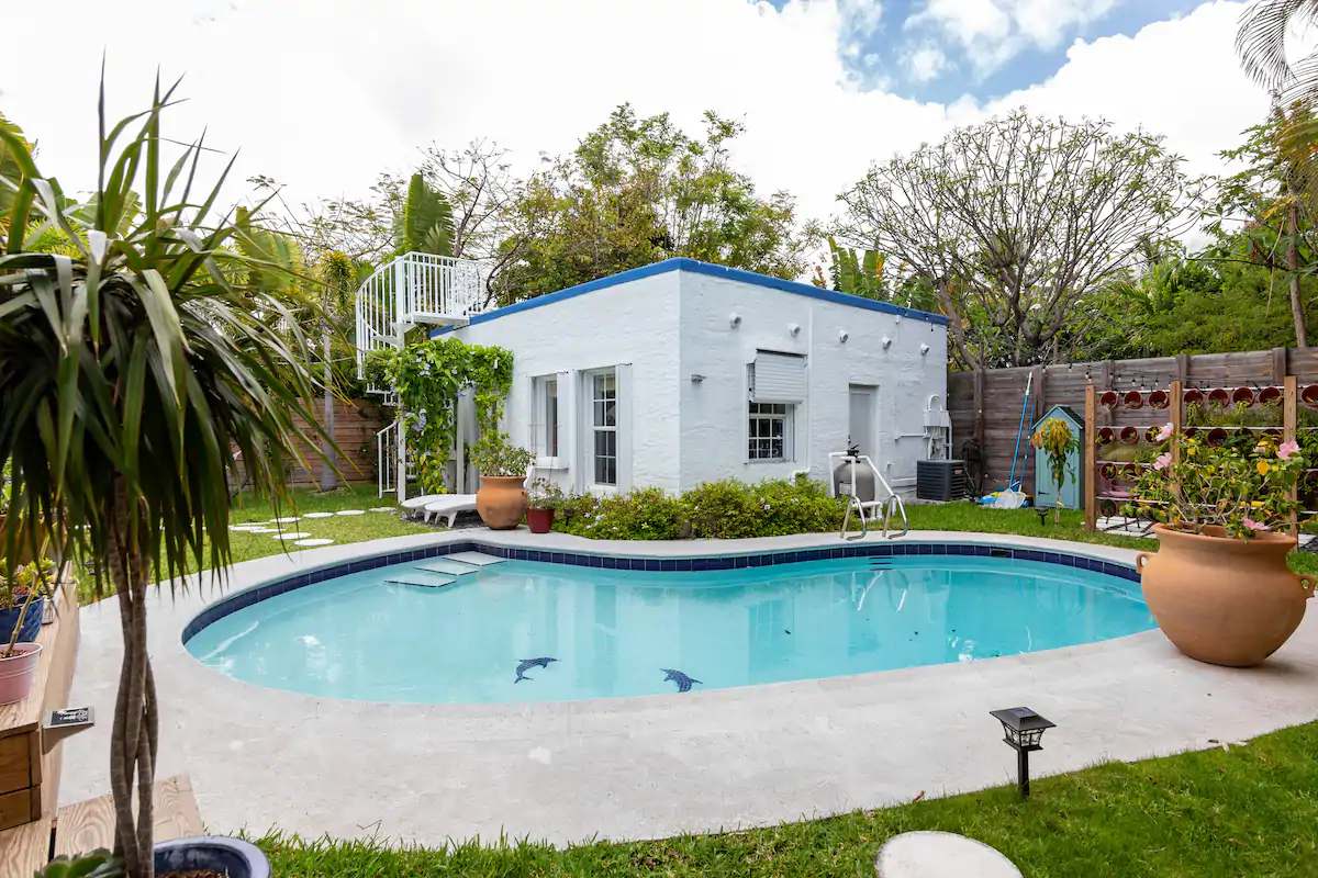white and dark blue square cottage with a blue inground pool next to it at one of the best airbnbs in miami