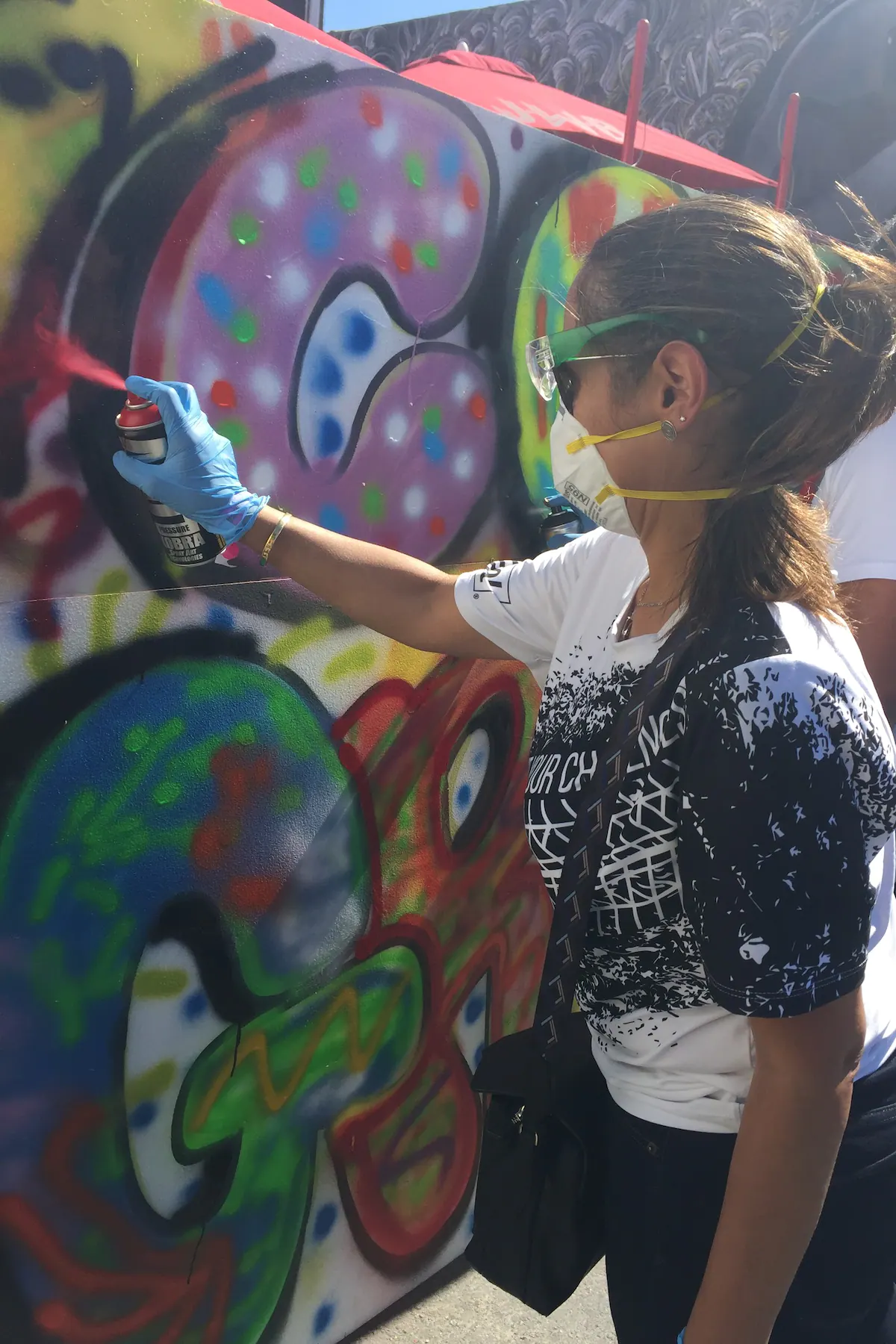 girl spray painting a colorful mural in wynwood while traveling in miami