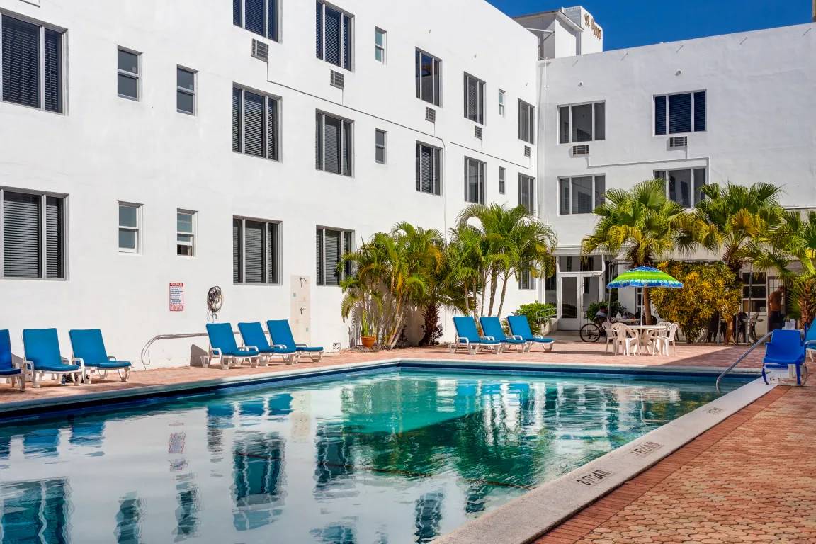 in ground pool with turquoise water and a white building surrounding it