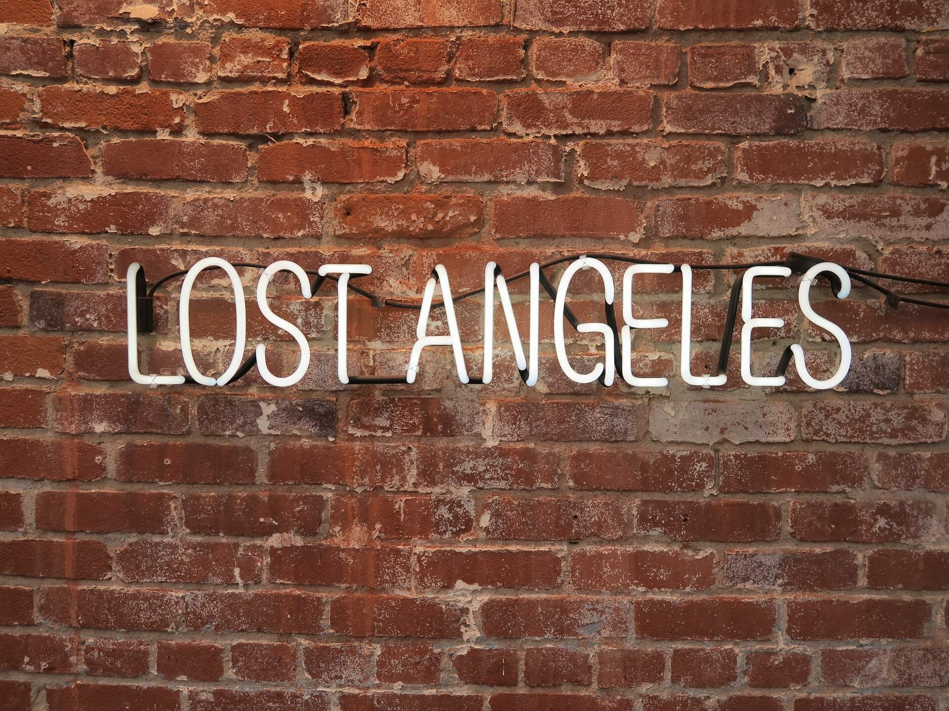 sign says lost angeles in white neon plastic against a brick wall background