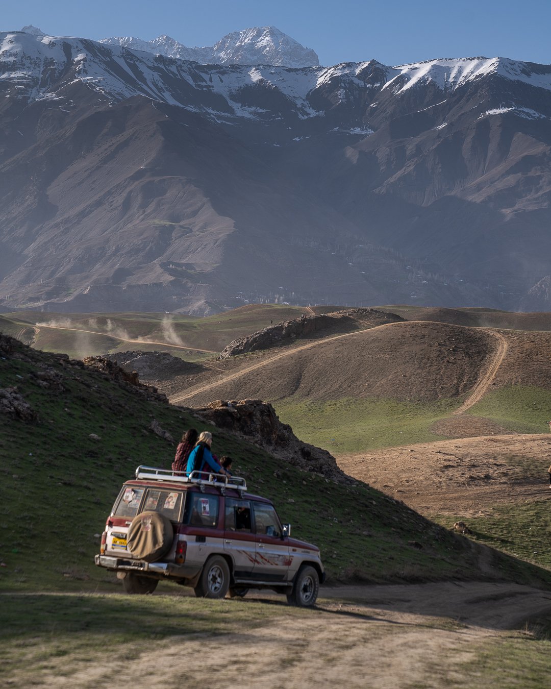 girls sitting on top of a 4wd car in green meadow in pakistan