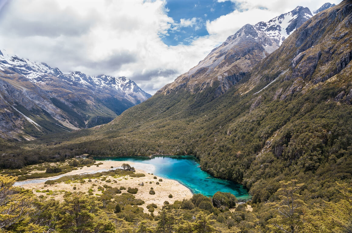 A blue lake nestled amidst snow-capped mountains in Nelson Lakes National Park, New Zealand.
