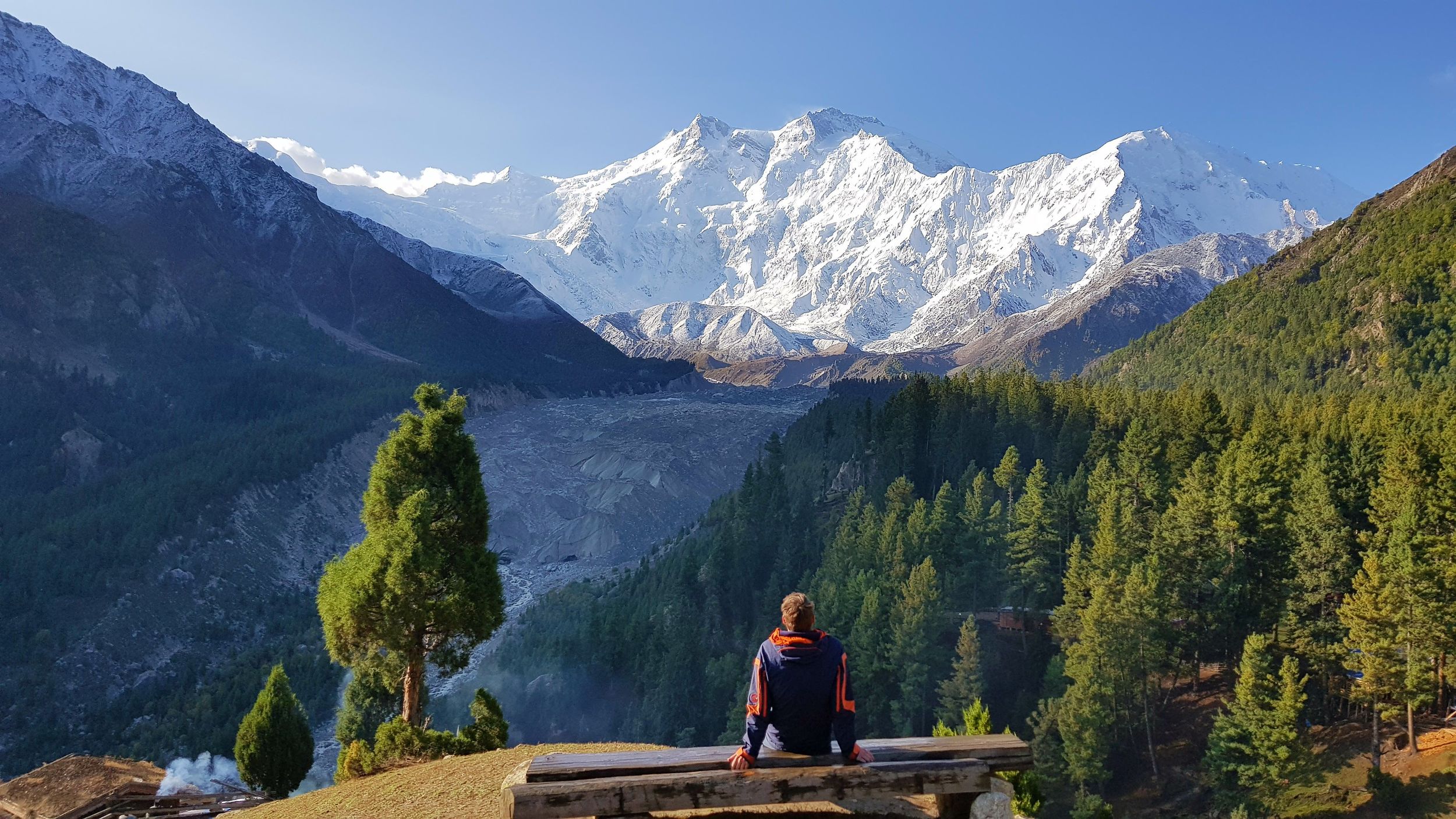 man sitting looking at a mountain view, nanga parbat in fairy meadows pakistan