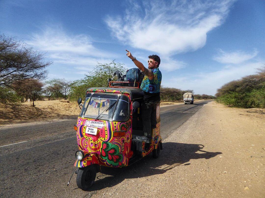 Will hanging out of the side of a Rickshaw and pointing in India