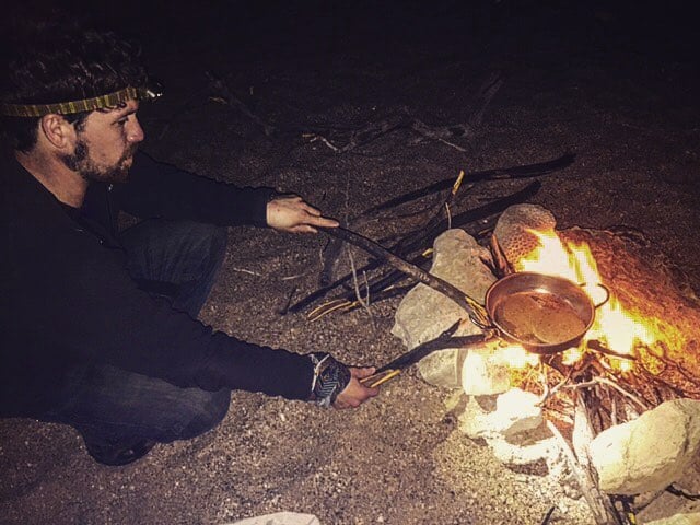 man wearing a headlamp while lighting a camp fire in iran