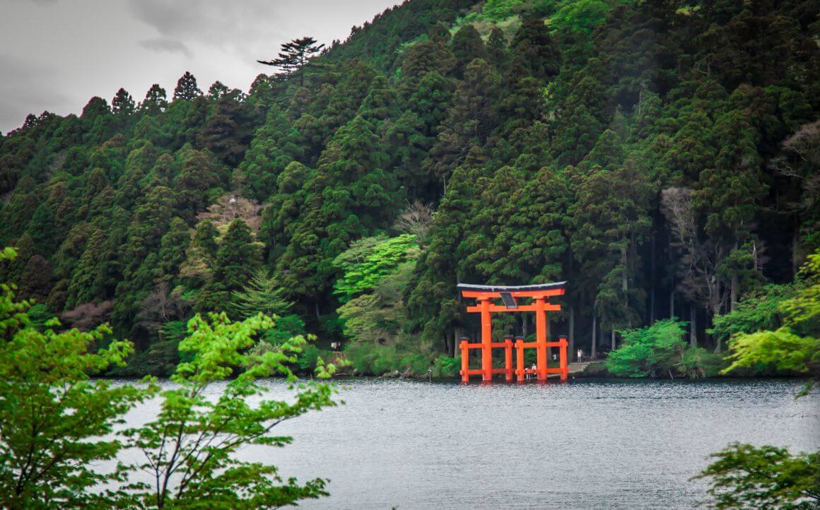 Red torii gate  in the middle of Lake Ashi, Hakone surrounded by lush greenery