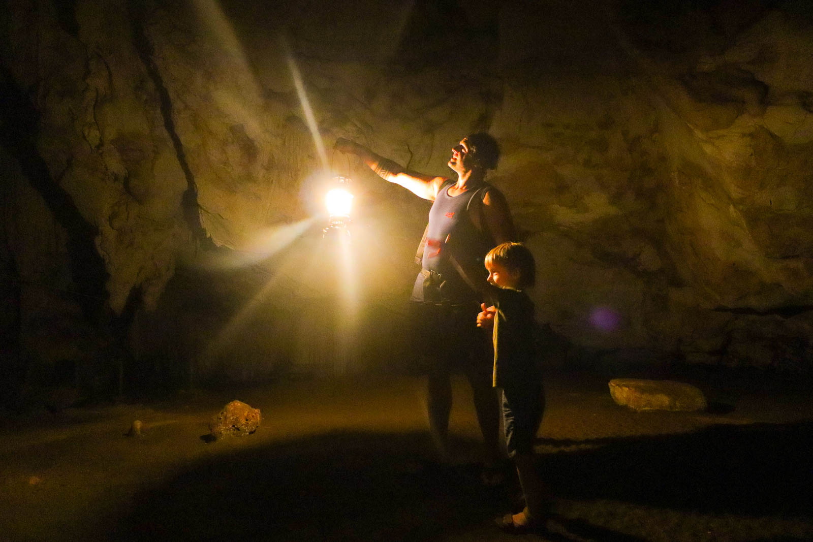 man and his son exploring a dark cave while living a life of full time family travel