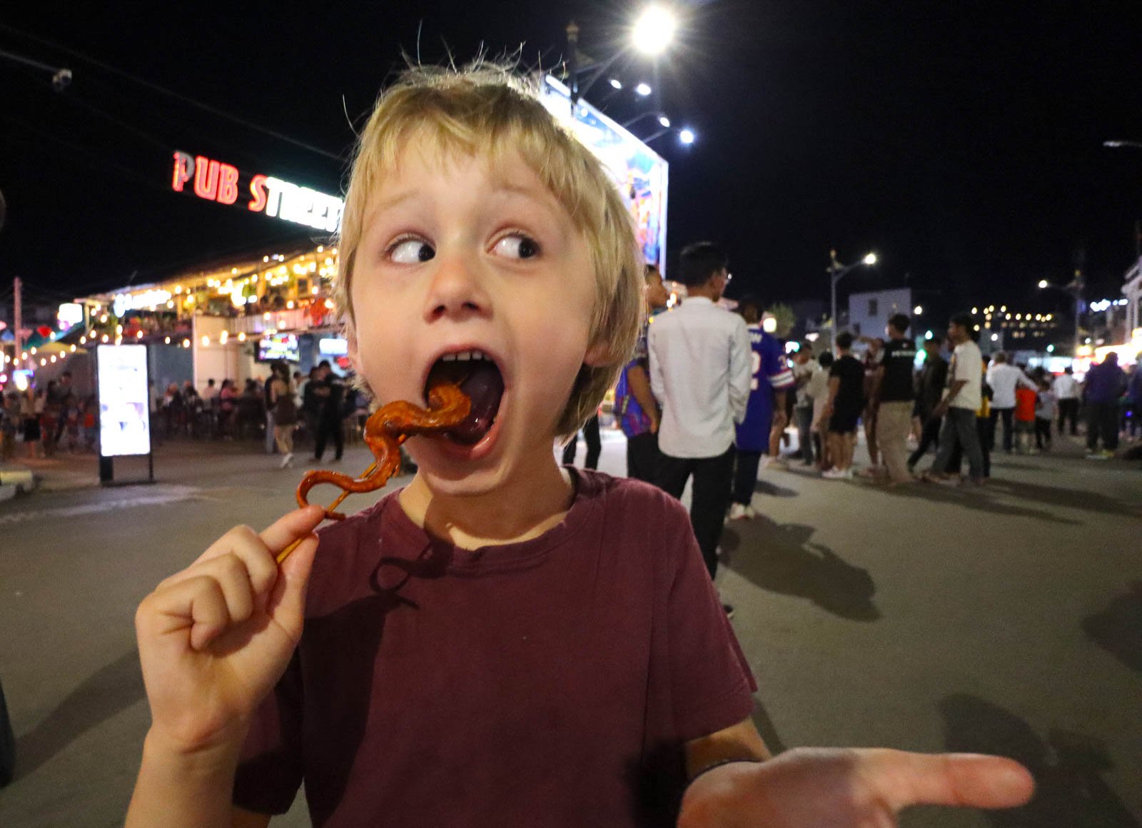 young boy eating street food on a stick while doing full time family travel