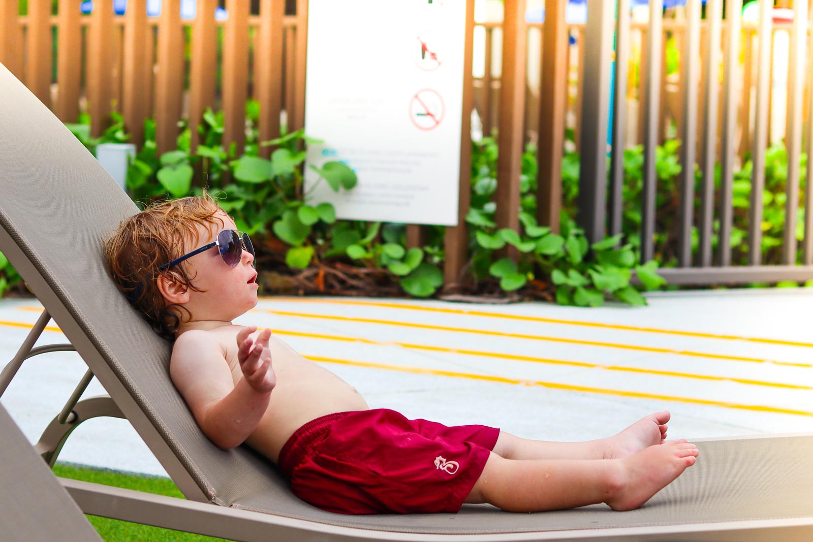 child wearing sunglasses and sitting in a deck chair in a warm place full time family travel
