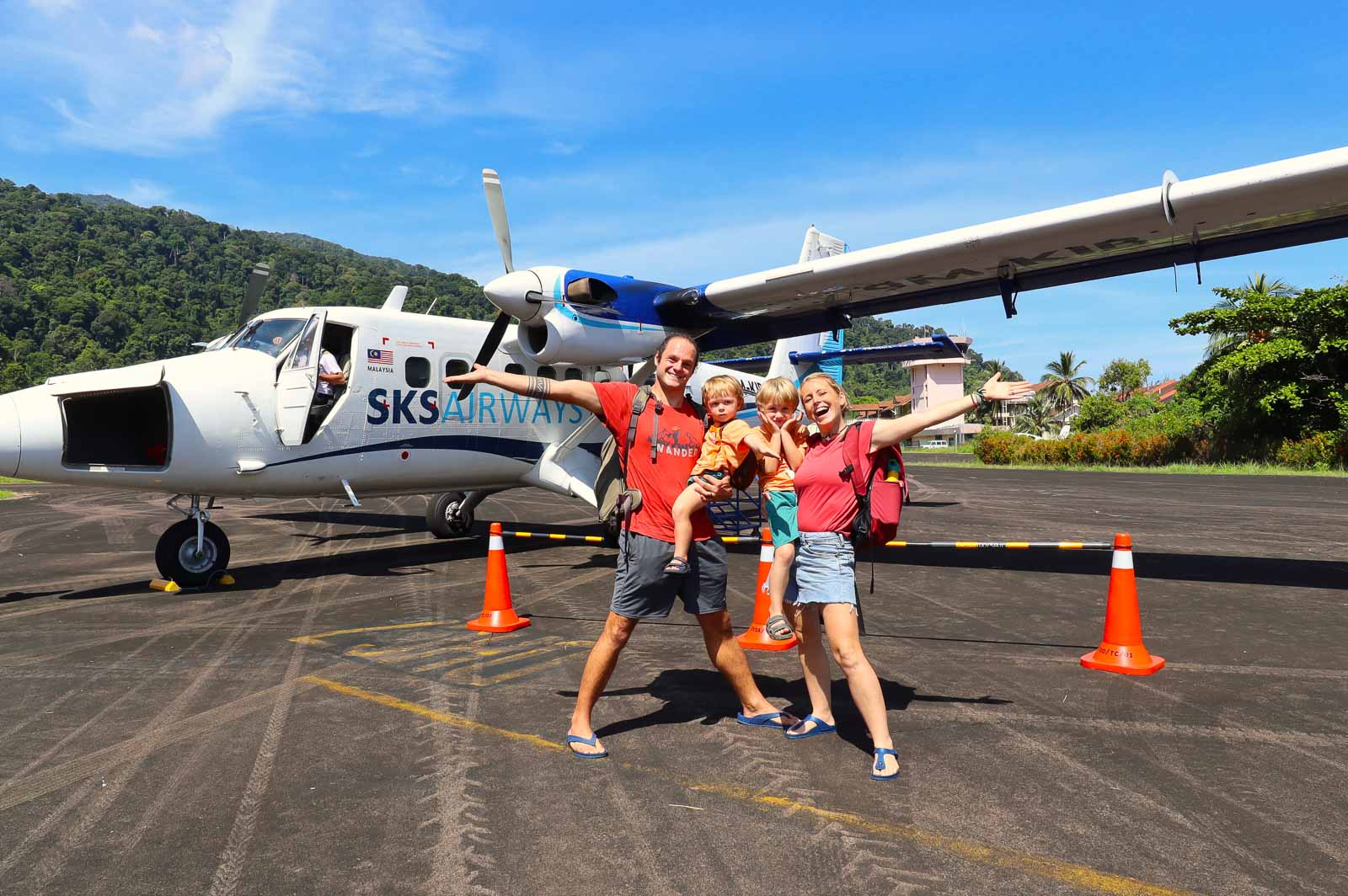 family of four standing in front of a small propeller plane full time family travel