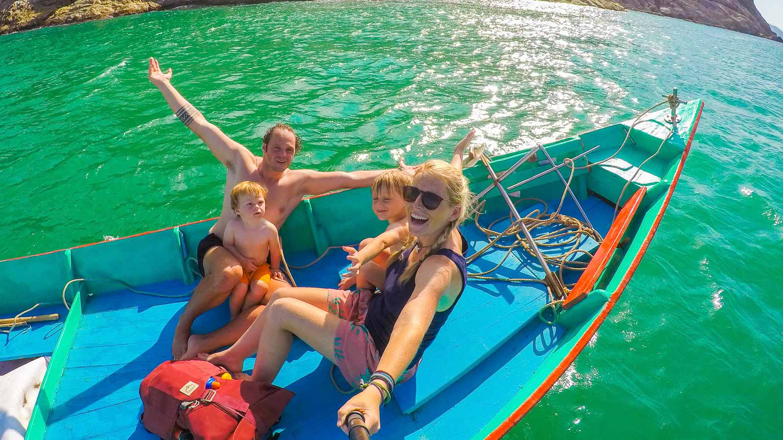 family sitting on a blue boat in turquoise water in thailand