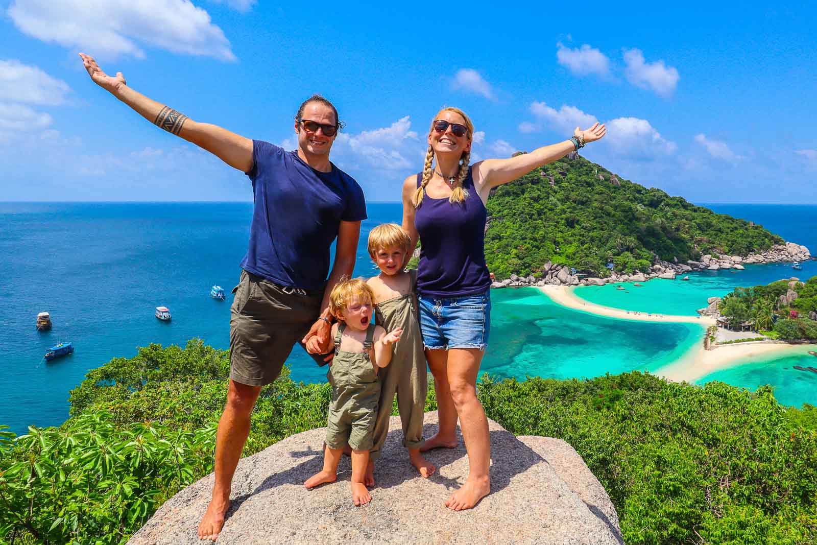 backpacking family standing on a viewpoint in thailand with a bright blue sea beneath