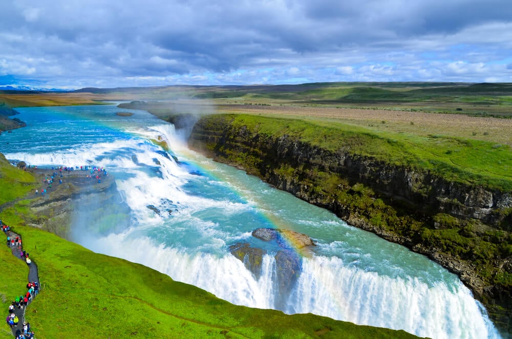 bright blue gulfoss falls in icealnd set amongst emerald green meadows