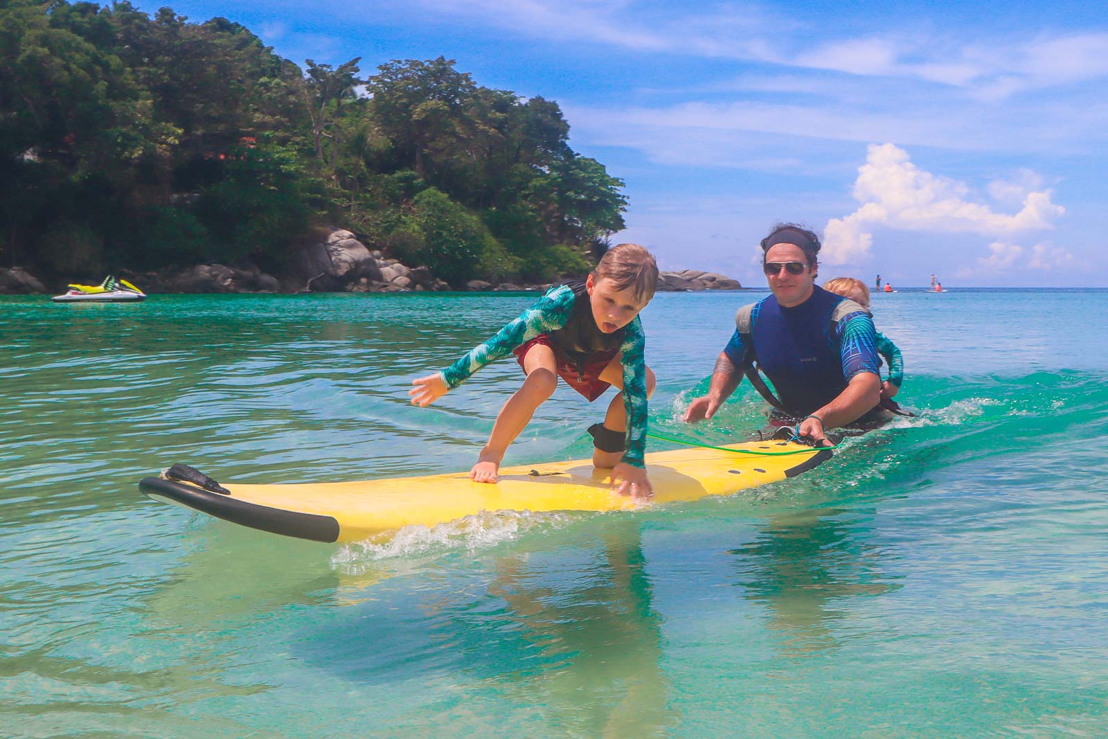 kid learning to surf on turquoise water in thailand